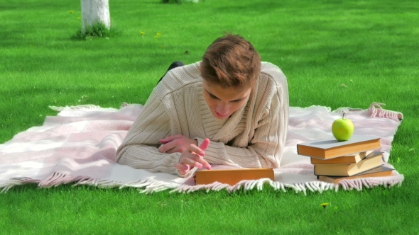 Young Smiling Man Lying With Tablet On Lawn alt