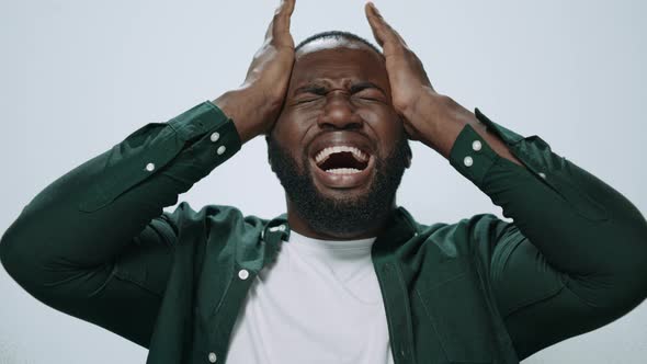 Portrait of Exhausted African Man Holding Hands on Head at Grey Background alt