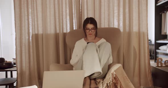 Young Woman Sits on Armchair Working on Mobile Phone at Home Texting Message alt