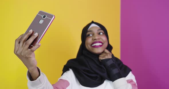 Portrait of Smiling African Muslim Female Taking Selfie on Smart Phone alt