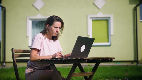 Woman works with laptop on backyard