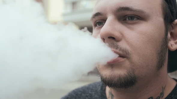 Young Man Smoke E-Cigarette. Vape. 