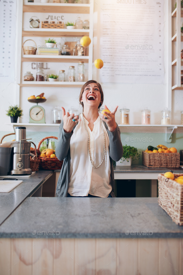 Young woman juggling with fruits at juice bar