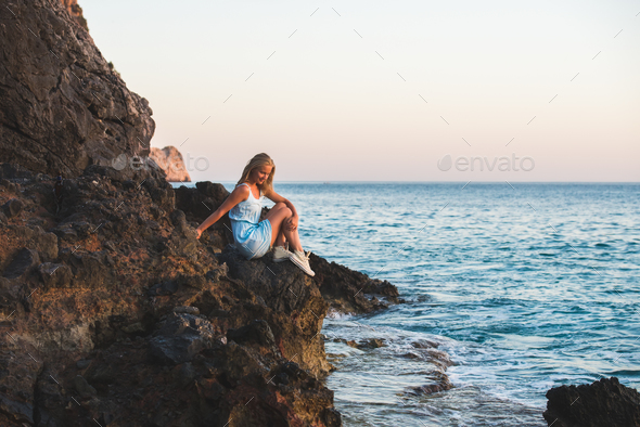 Young blond woman tourist in blue dress sitting - Stock Photo - Images