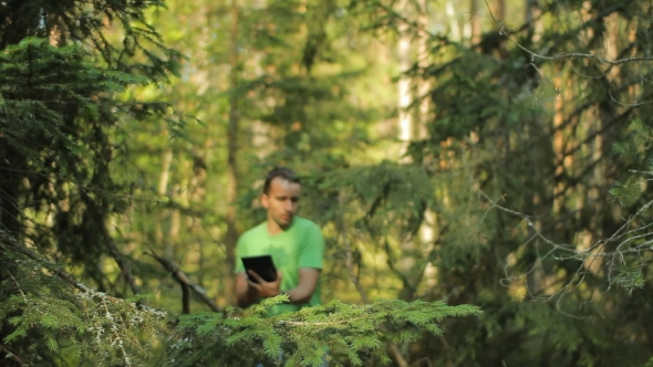 A Man Walks Through The Forest With a Tablet PC And Looking At The Navigation Application.