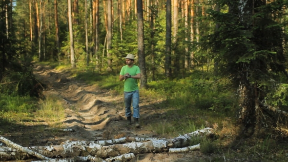 A Man Walks Through The Forest With Smart Watch And Looking At The Navigation Application.