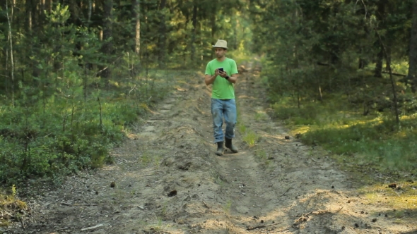 A Man Walks Through The Forest With The Phone And Looks At The Navigation Application. He Chooses