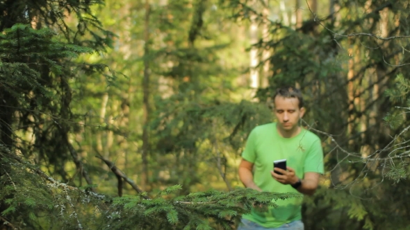 A Man Walks Through the Forest With the Phone