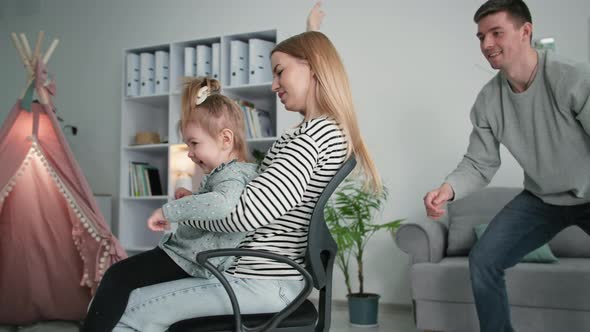 Happy Family Young Parents Woman and Man with Joyful Daughter Have Fun Together Man Rolls His Wife