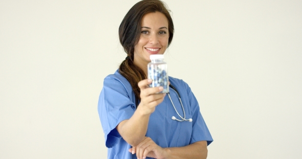 Young Brown Haired Doctor In Scrubs Holds Bottle alt