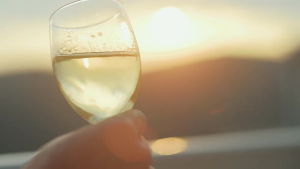 Attractive young fashion man in a suit  drinks white wine at sunset on the balcony of the house alt