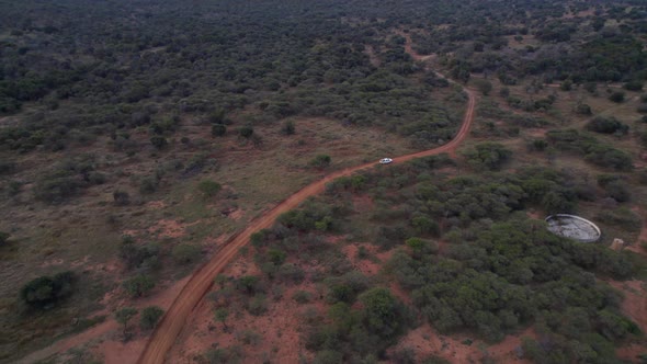 4x4 suv white vehicle driving a dirty road in African game reserve farm. Aerial alt