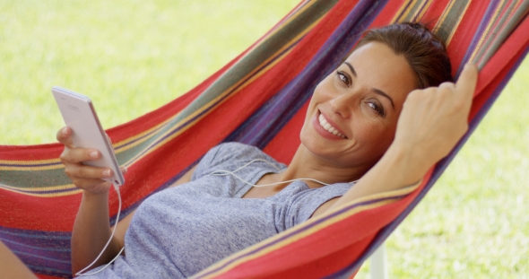Happy Young Woman Listening To Music In a Hammock alt