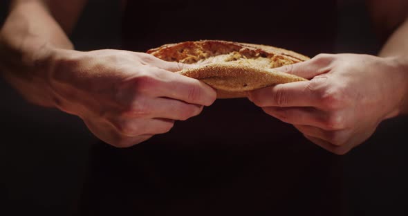 A Man Tears A Loaf Of Freshly Baked Bread In Half. Home Bakery