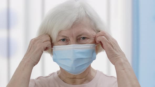 Crop View of Senior Elderly Woman with White Hair Taking Off Medical Protective Mask and Looking to alt