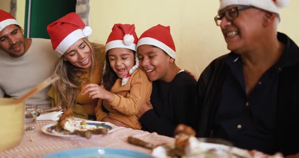 Happy latin family eating dinner together at home while celebrate Christmas time alt