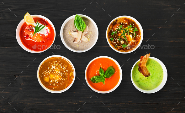 Variety of soups at black wood, top view