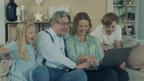 Grandparents and Grandkids Are Using a Laptop and Laughing alt