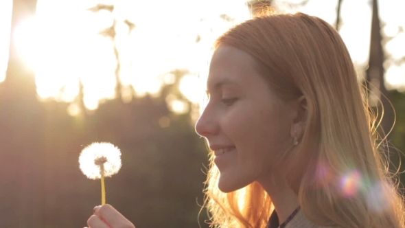 Side View Of Blonde Girl Blowing On Dandelion