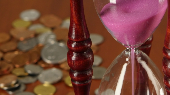 Hourglass On Coins Background.  alt