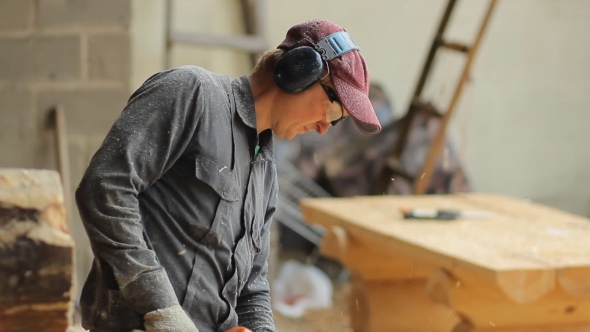 Man Working With a Chainsaw. Wood Shavings Are Flying Saw His Face. 