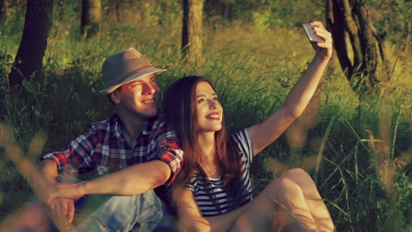 A Young Couple Takes The Photo On The Green Grass On Park Background ...