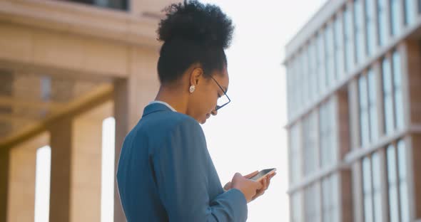 African Young Businesswoman Wearing Suit Using Smartphone in City alt