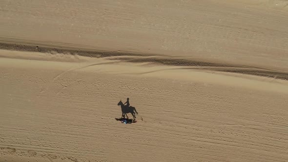 Aerial view of one person riding horse in the desert of Al Khatim in Abu Dhabi. alt