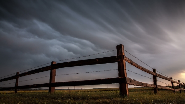 Fence In The Field Under Stormy Cloud Sky
