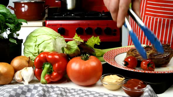 Chef Decorates Fried Meat in Plate with Fried Cherry Tomatoes and Rosemary alt