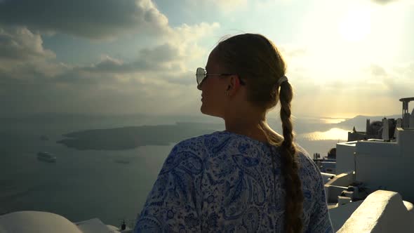 Happy Woman in White and Blue Dress Enjoying Her Holidays on Santorini, Greece alt