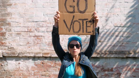 Woman shows cardboard Go Vote  sign Voting balloting polling Political choice elections voice 4K