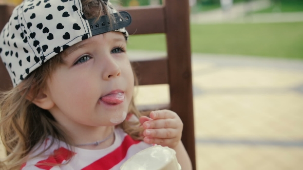Little Girl Sits On The Chair And Eats Ice Cream