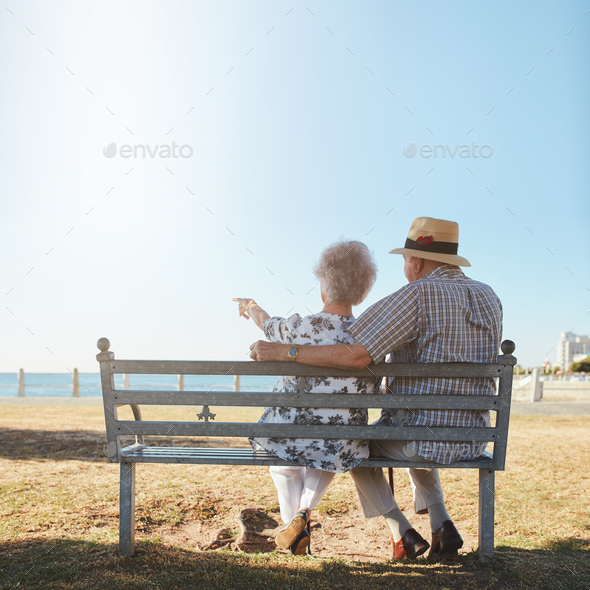 Senior couple sitting on bench looking out to sea