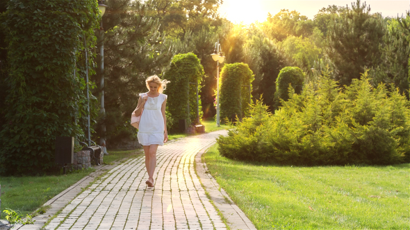 Beautiful Girl Walking Alone in the Park at Sunset alt