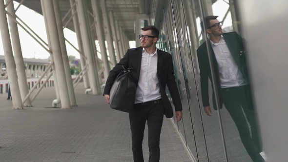 Young Businessman Pulling Suitcase In Modern Airport Terminal. Travelling Guy Concept