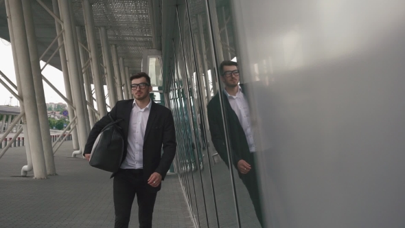 Young Confident Businessman With Suitcase In Modern Airport Terminal. Travelling Hipster Guy Concept