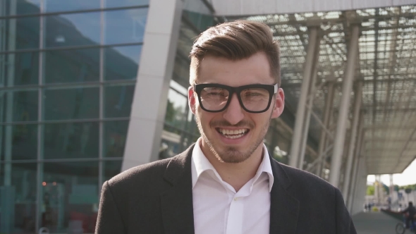 Face Of Confident Handsome Smiling Businessman Adjusting Glasses And Staring At The Camera. Outdoor