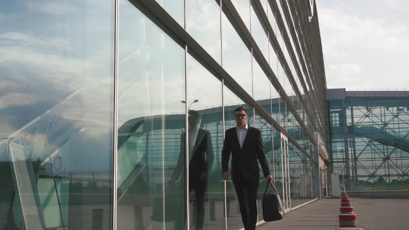 Attractive Young Bearded Businessman In Glasses Goes For Boarding To His Plane. Glass Airport Wall