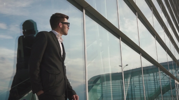Attractive Young Bearded Businessman In Glasses Waiting For His Flight And Relying On The Glass