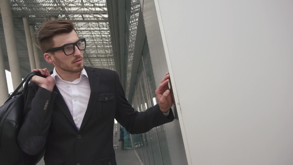 Business Hipster Man With Luggage Waiting For His Flight. Male Businessman Model In Glasses On The