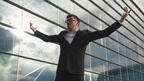 Successful Attractive Businessman Standing With His Arms Raised Up As a Winner And Smiling. Glass