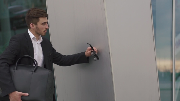 Anxious Young Businessman Hiding From Someone At The Wall. Urban City Background