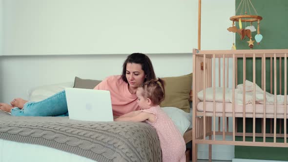 Mom Works Using Laptop While Lying on Bed with Baby alt