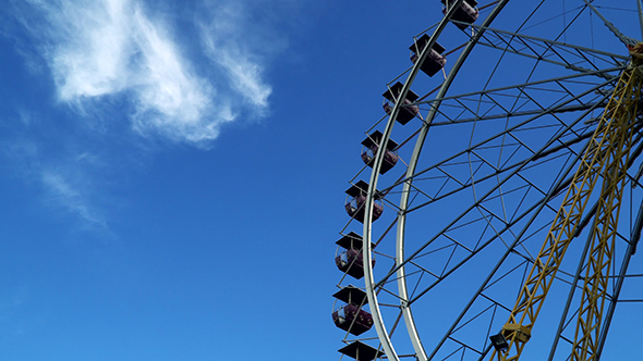 Rotating Ferris Wheel Against the Sky With Clouds