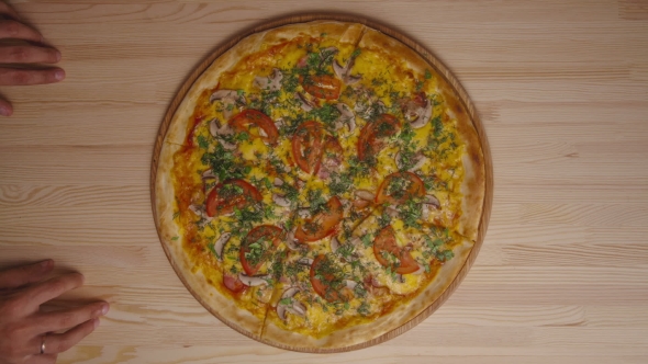 Hands Of Hungry Man Moving Tasty Pizza On Kitchen Table