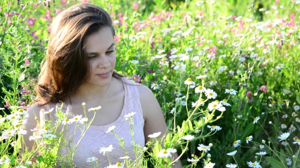 Beautiful Girl Sees Daisies in Meadow