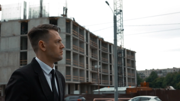 Businessman In Suit Walking Near Newly Constructed Building alt