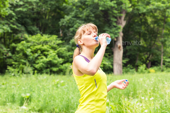 Fitness beautiful woman drinking water and sweating after exercising on summer hot day
