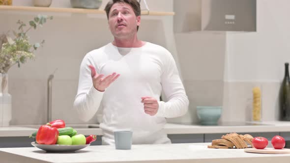 Happy Middle Aged Man Dancing While Drinking Coffee in Kitchen alt